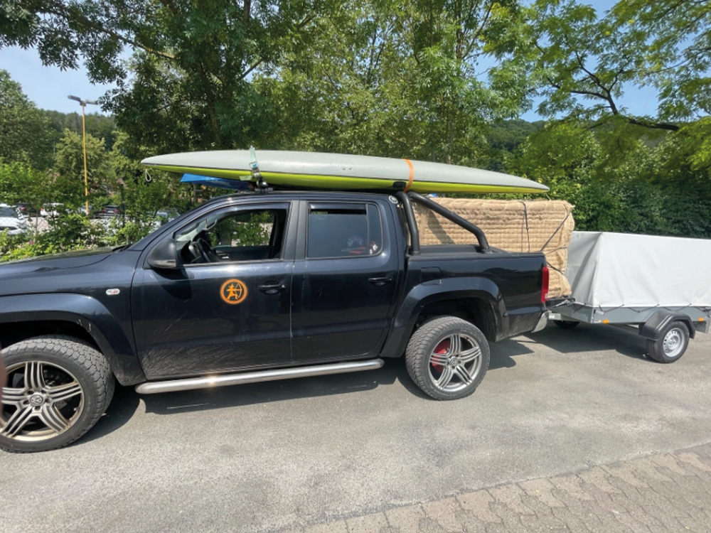 Hier sehen Sie ein Bild von einem VW Amarok, mit einem Surfboard und Anhänger
