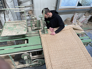 in diesem Bild sieht man wie die Schnittkanten mit Jute zugenäht werden, damit Fasern nicht rausfallen und bröseln